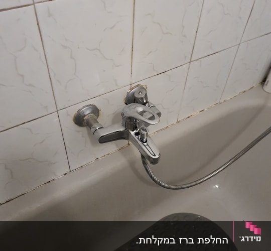 ברז אמבטיה עם צינור גמיש על קיר אריחים